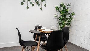Un'area pranzo con un tavolo rotondo, sedie nere e una pianta di bambù.