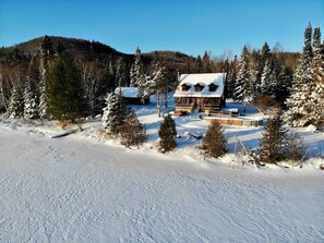 A cabin surrounded by snow-covered trees and a clear sky.