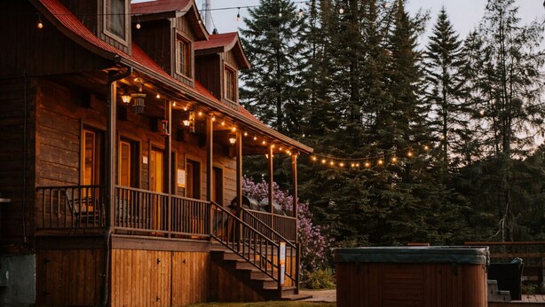 A wooden cabin with a porch, outdoor seating, and a hot tub. - Le Martini Bord de l eau, spa, piscine. (Entrelacs)