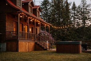 A wooden cabin with a porch, outdoor seating, and a hot tub. - Le Martini Bord de l eau, spa, piscine. (Entrelacs)