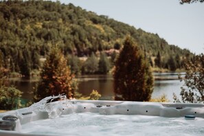 A hot tub with a view of a forested lake.