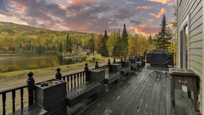 Una terraza de madera con vistas a un lago y árboles otoñales.