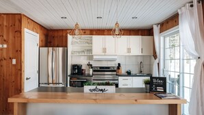 Una cocina moderna con paredes de madera, electrodomésticos de acero inoxidable y una isla central con taburetes de bar.