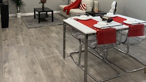 Un salon moderne avec un coin repas, des murs gris et un parquet en bois gris.