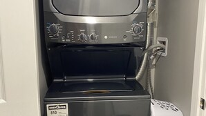 Une machine à laver compacte et moderne, dotée d’un panneau de commande et d’un tuyau d’arrivée d’eau.