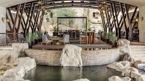 A spacious outdoor seating area with a central stage, surrounded by large rocks and a water feature.