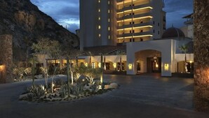 A multi-story hotel with a central courtyard featuring desert landscaping and a stone wall.