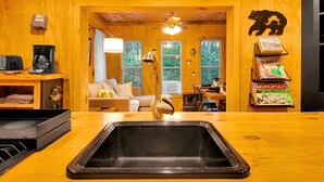 Un intérieur en bois comprenant un évier, un ventilateur de plafond, un canapé et une machine à café.