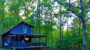 Une cabane avec une véranda, un panneau lumineux et une terrasse.