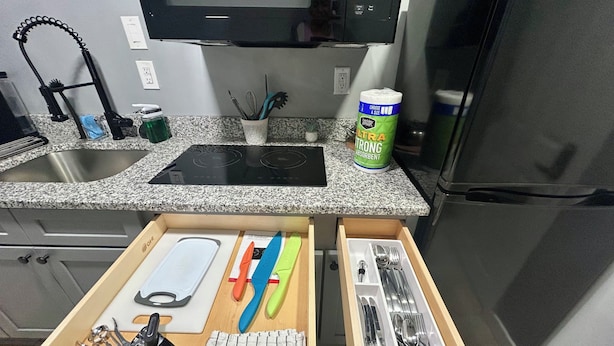 Eine Küche mit Granit Arbeitsplatte, einer Mikrowelle, einem Kühlschrank und einem Schubladeneinsatz für Besteck.