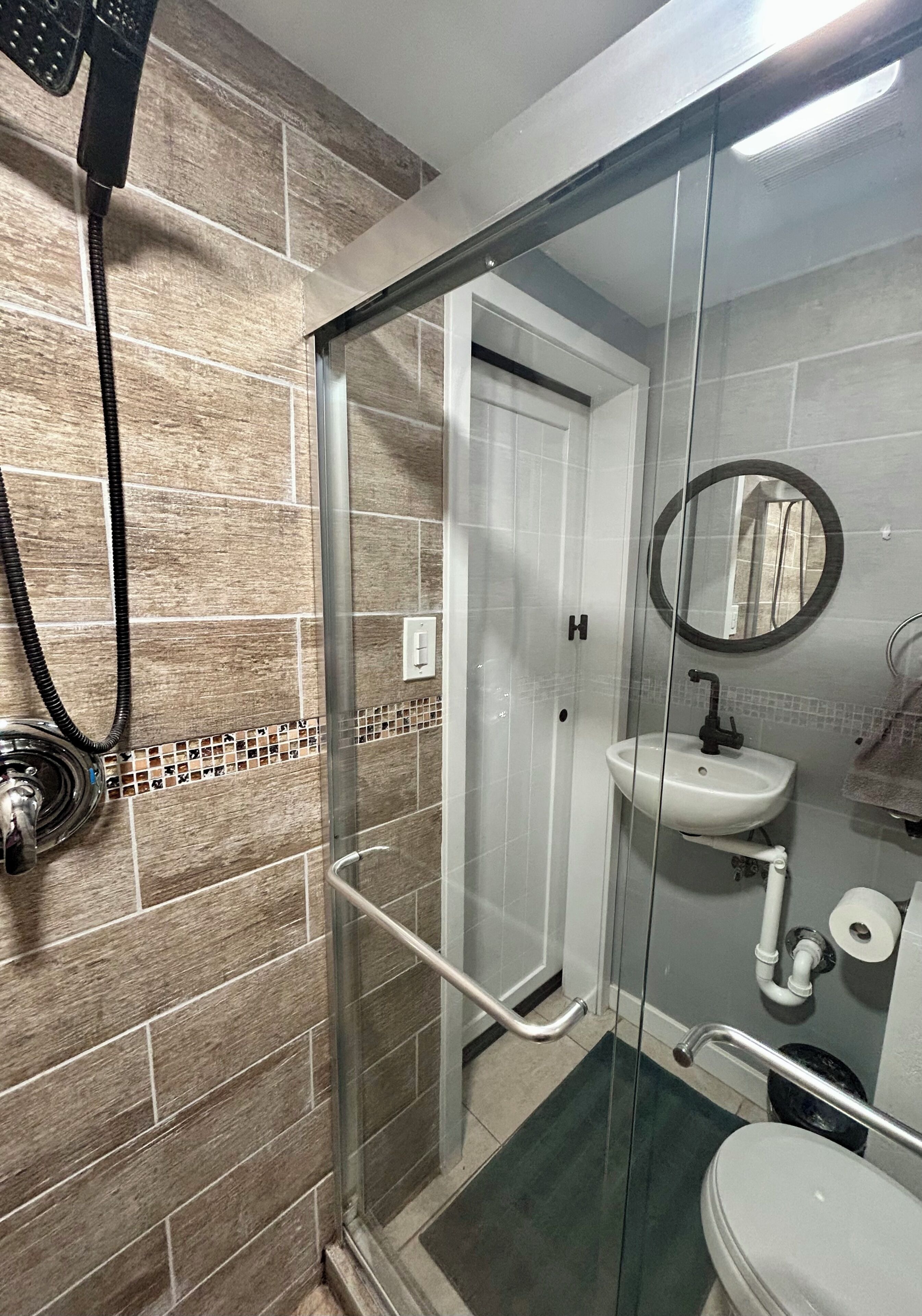 Une salle de bain avec une douche à parois de verre, un lavabo blanc et des toilettes.