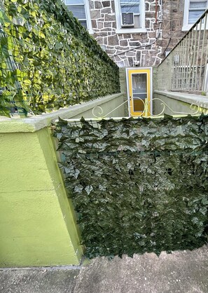 Een stenen gebouw met een gele deur, een groene muur en een haag.