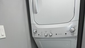 Ein Waschbereich mit einer Waschmaschine mit Frontlader und einem Tisch mit Reinigungsmitteln und gefalteten Handtüchern.