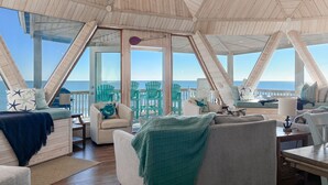 A spacious, open-plan living area with a view of the ocean, featuring wooden architecture and comfortable seating. - Oceanfront Seaside Stargazer+Hot Tub+Pets OK+Infinity Table+Beach Gear+4 Kings (North Topsail Beach)