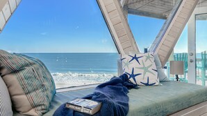A room with a view of the ocean, a bed with a book, and a star-patterned pillow. - Oceanfront Seaside Stargazer+Hot Tub+Pets OK+Infinity Table+Beach Gear+4 Kings (North Topsail Beach)