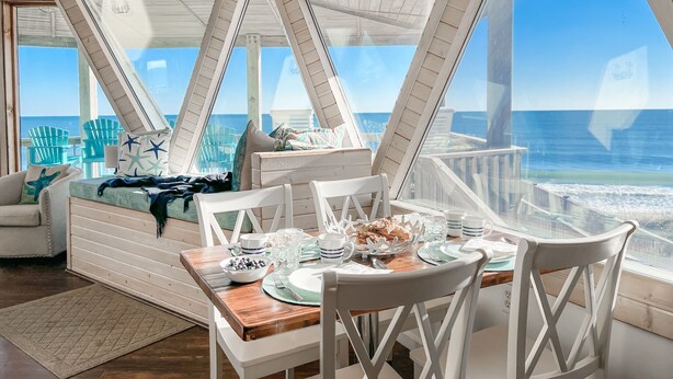 A cozy room with a wooden ceiling, large windows, and a view of the ocean. - Oceanfront Seaside Stargazer+Hot Tub+Pets OK+Infinity Table+Beach Gear+4 Kings (North Topsail Beach)