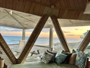 Habitación frente a la playa con vista al océano, vigas de madera y una terraza de madera.