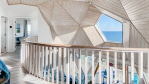 A spacious room with a high ceiling and a large skylight, offering a view of the sky and sea. - Oceanfront Seaside Stargazer+Hot Tub+Pets OK+Infinity Table+Beach Gear+4 Kings (North Topsail Beach)
