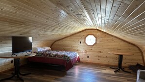 Een gezellig slaapkamer op zolder met een bed, een televisie en een klein tafeltje.