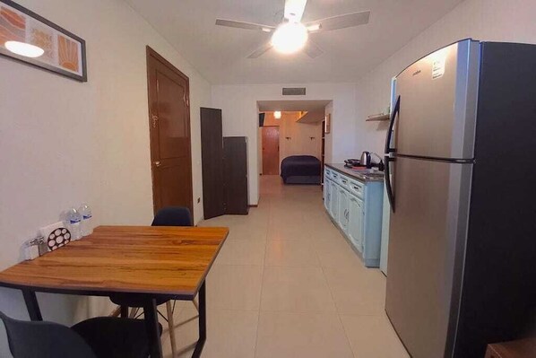 Una cocina compacta con refrigerador, una mesa de comedor y sillas.