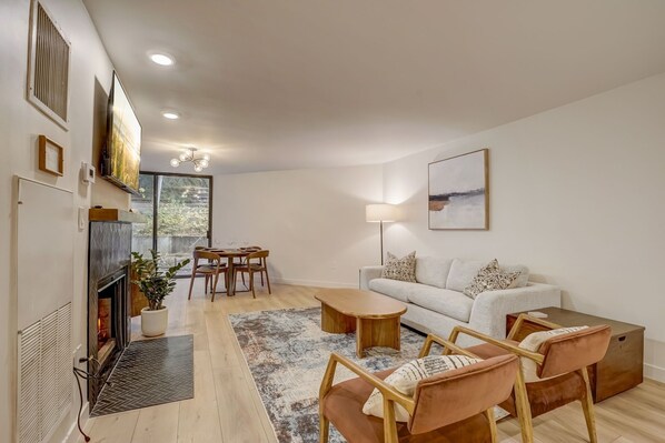 Una sala de estar moderna con chimenea, un sofá, una mesa de centro y un comedor.