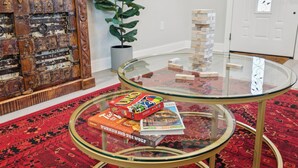 Una habitación con una mesa de vidrio que sostiene libros y una torre de Jenga.