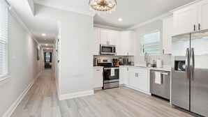 Una cocina moderna con armarios blancos, electrodomésticos de acero inoxidable y piso de madera.