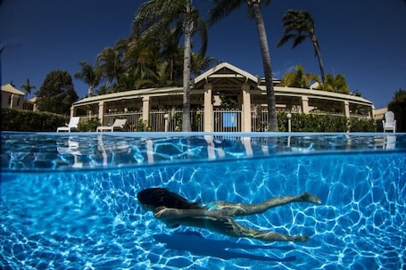 Una piscina al aire libre, sombrillas, sillones reclinables de piscina