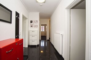 A hallway with a red cabinet, a white filing cabinet, and a radiator. - Ferienwohnung Cosmo - Direkt am Waldrand mit Balkon und in Strandnähe - Ferienwohnung Cosmo (Glowe)
