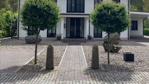 Een modern huis met twee verdiepingen, een symmetrische gevel, grote ramen en een centrale ingang.