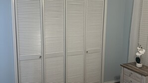 A bedroom with a large closet labeled 'DIAMONDHEAD', a wooden nightstand, and a bed with a white comforter. - The Dolce Cabana located on the golf course in beautiful Diamondhead, MS. (Diamondhead)
