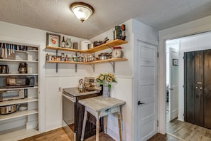 A kitchen with wooden shelves, a stove, and various kitchen appliances. - Near Beach: Coastal Maine Getaway w/ Yard (Wells)