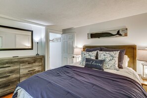Un dormitorio con cama, cómoda, espejo, una obra de arte en la pared y una puerta.
