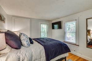 A bedroom with a bed, pillows, a flat-screen TV, and windows. - Near Beach: Coastal Maine Getaway w/ Yard (Wells)