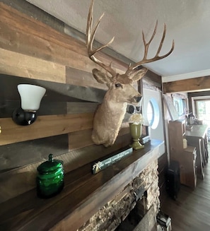 A deer head mounted on a wooden shelf, a green jar, and a candle holder.