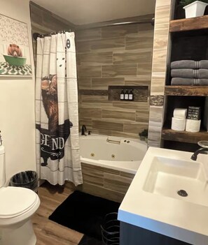 Une salle de bain équipée d’une baignoire, de toilettes, d’un lavabo et d’un rideau de douche orné d’un motif d’ours.