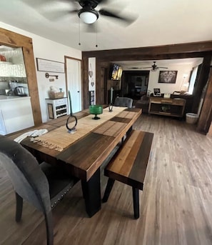 A dining area with a wooden table, benches, and a ceiling fan.