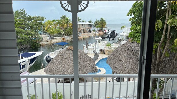 Vista de varanda com vista para uma marina com barcos, piscina e área de resort.