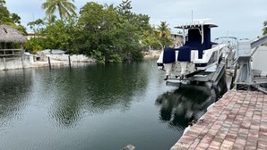 Um cais com um barco, água calma e uma construção de telhado de palha.