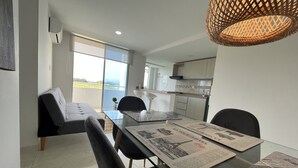 Un salon moderne avec une table à manger en verre, des chaises noires et un canapé.