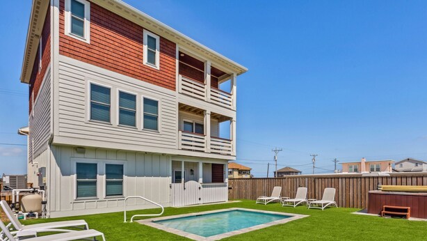 A two-story house with a swimming pool, a fenced backyard, and a wooden deck.