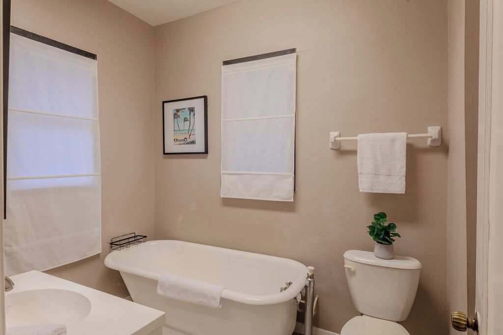 Une salle de bain avec une baignoire, des toilettes et un lavabo. Deux serviettes sont accrochées au mur.
