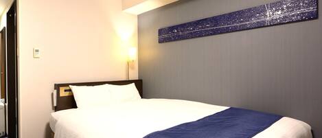 Una habitación de hotel con una cama, una mesita de noche, una lámpara de pared y un cuadro.