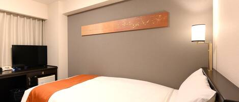 Habitación de hotel con cama, televisor de pantalla plana, escritorio con ordenador y un cuadro en la pared.
