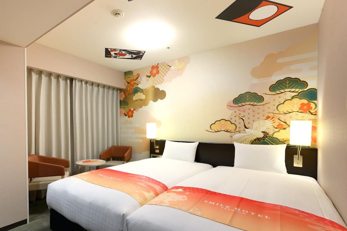 Une chambre d’hôtel avec un grand lit, un bureau, une chaise et une fenêtre avec des rideaux.