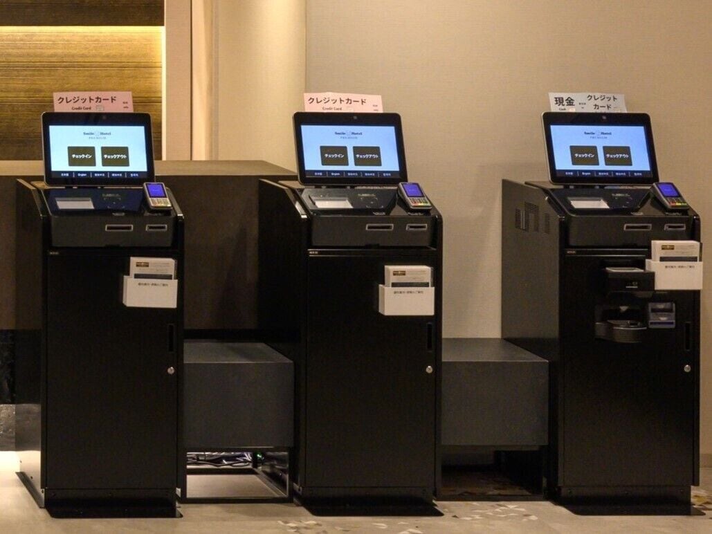 Three self-service kiosks with screens displaying payment options.