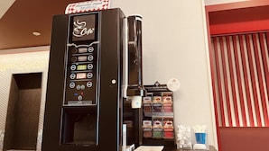 Een koffieautomaat voor zelfbediening met diverse drankjes, een selectie theesoorten en een menukaart.