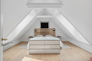 Ein Schlafzimmer mit schrÀgen WÀnden, einem Bett mit Holz Kopfteil, zwei Nachttischen und einer Heizung.