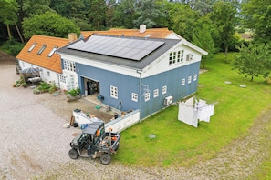 A two-story building with a solar panel roof, a covered outdoor seating area, and a vehicle parked in front. - Rural charm and beautiful landscape (Svebølle)