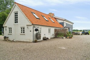Ein weiĂes GebĂ€ude mit rotem Ziegeldach, einem sichtbaren Fenster und einem Schild mit der Aufschrift 'GĂ€sthaus'.